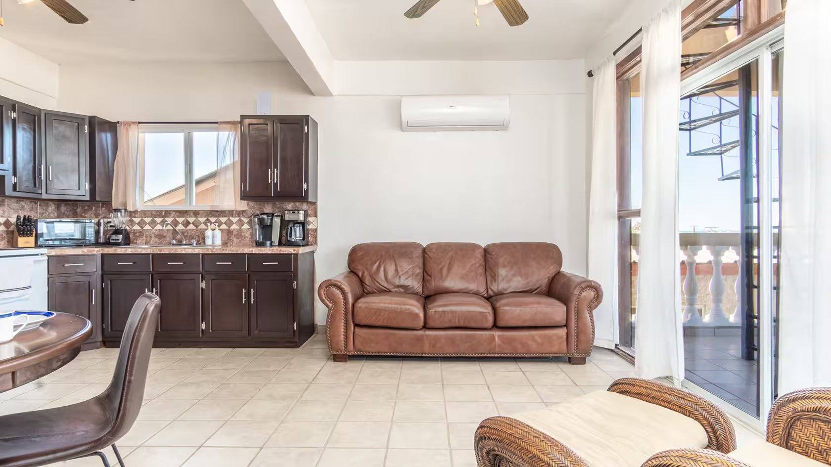 Open living room and kitchen at Cholla Bay Vista with leather sofas and an air conditioning unit
