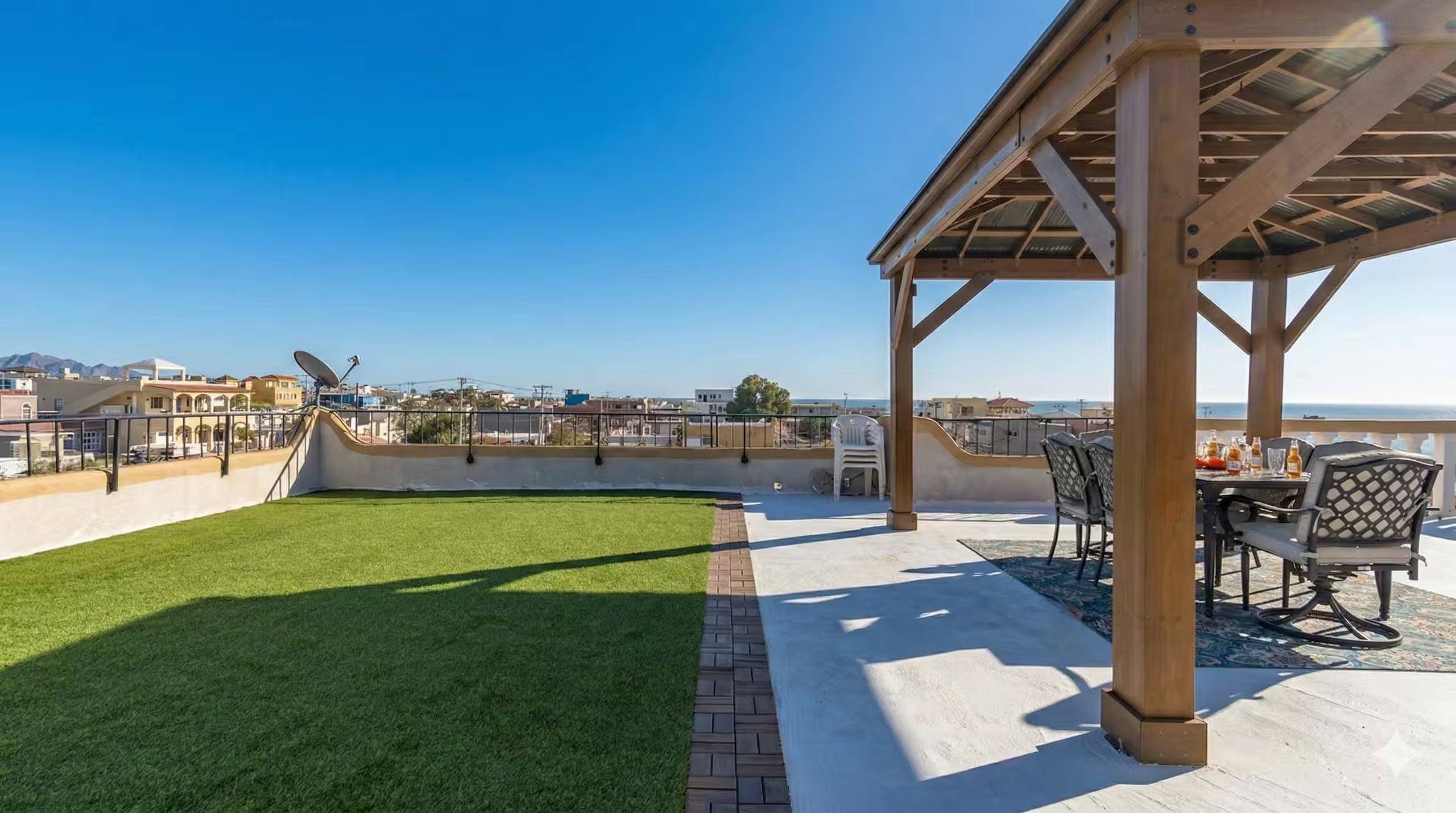 Rooftop turf lawn and covered palapa at Cholla Bay Vista under a clear blue sky
